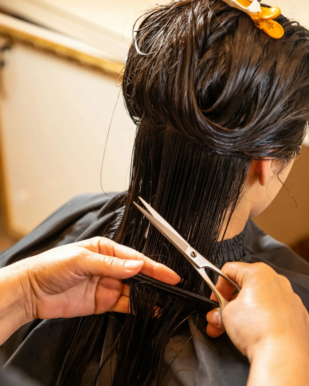 Eine Friseurin schneidet nasses, langes Haar mit der Schere (Symbolbild)